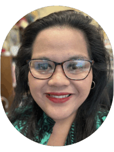 Close-up portrait of a person with dark, voluminous hair wearing hoop earrings and a green patterned top.