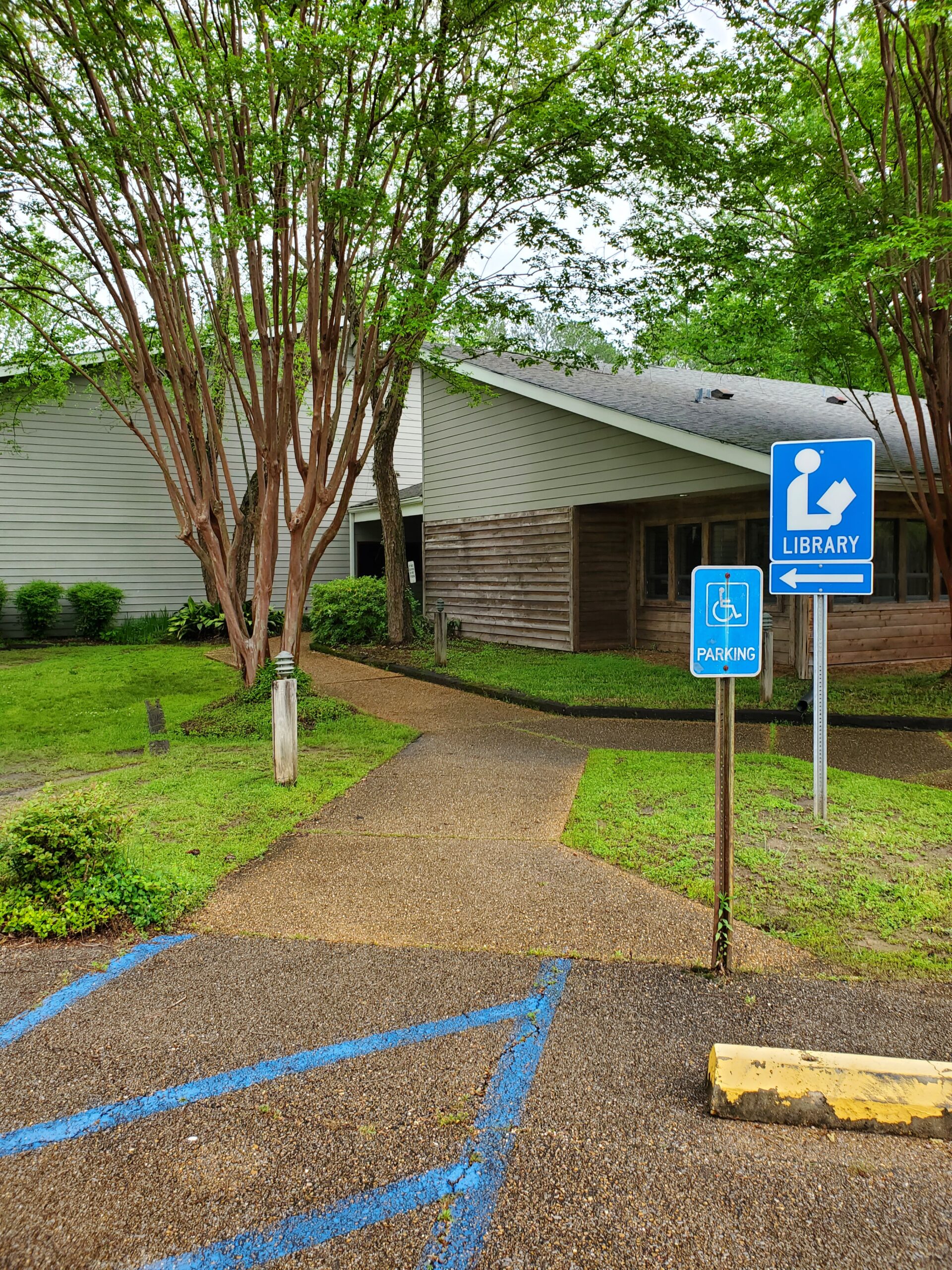 Grey library building with a tree in the front of it-Reservoir Public Library part of the Central Mississippi Regional Library System